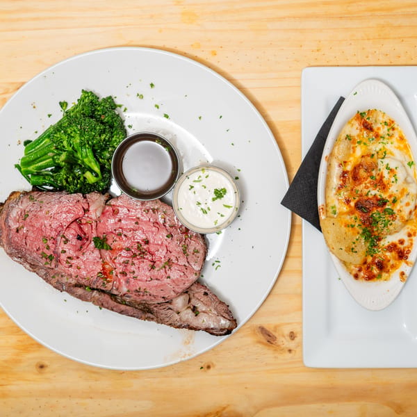 Prime rib with broccoli, au jus, horseradish sauce, and a side of scalloped potatoes.