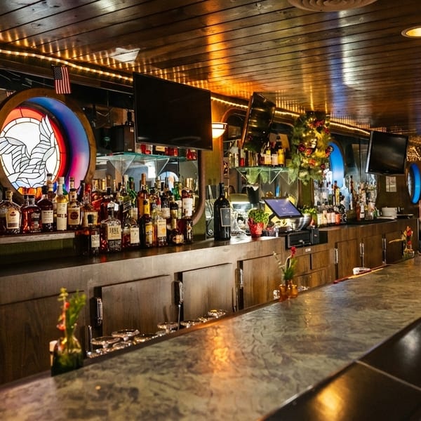 A long, well-stocked bar with bottles of liquor, a stained-glass window, and festive decorations.